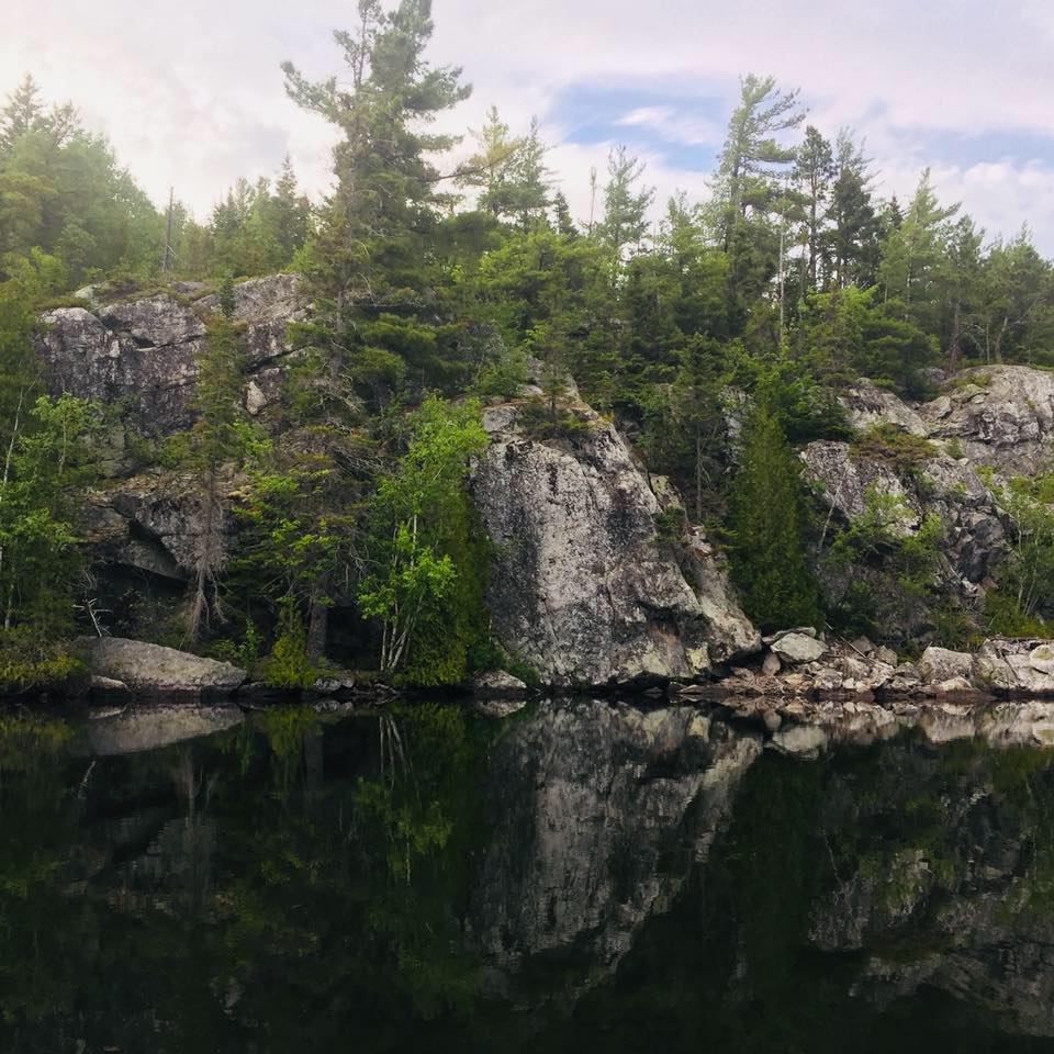 Falaise rocheuse et son reflet miroir dans les eaux calmes du lac