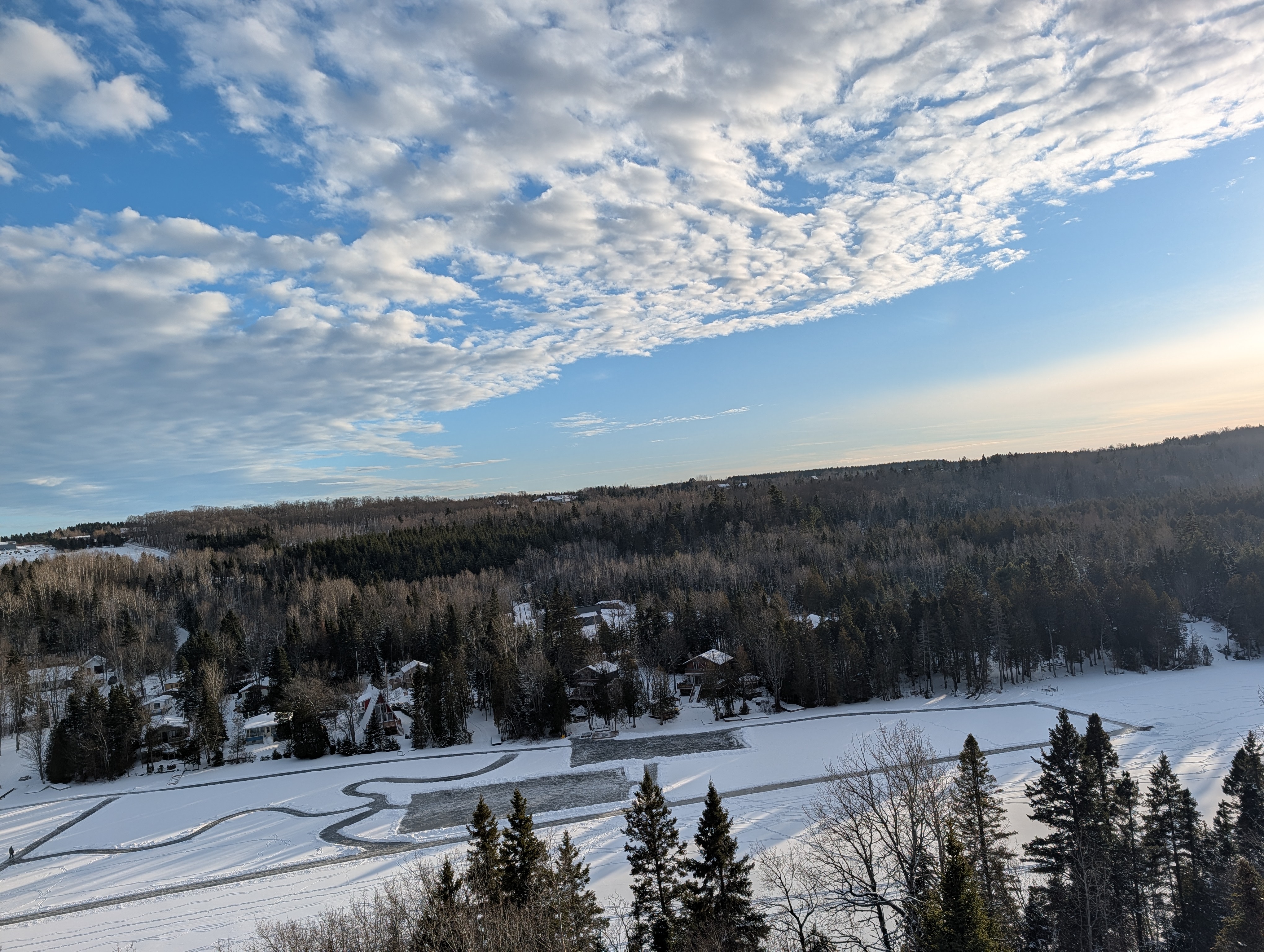 Vue aérienne hivernale du lac Saint-Pierre gelé avec chalets et forêt enneigée