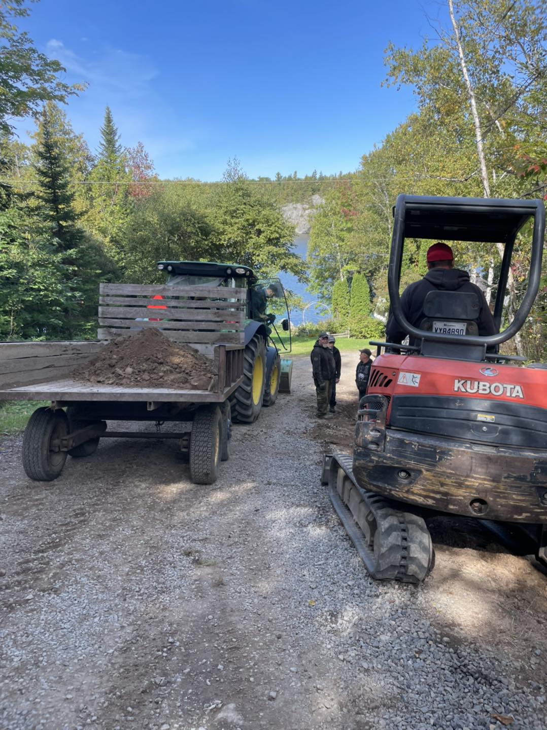 Tracteur et excavatrice préparant la terre pour la renaturalisation avec vue sur le lac