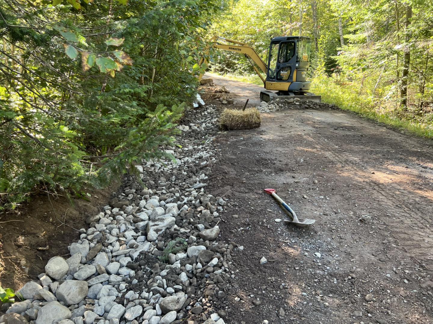 Mini-excavatrice travaillant sur le chemin forestier du lac