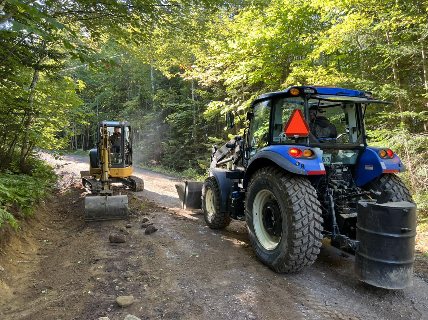 Deux véhicules lourds collaborant à la réfection du chemin